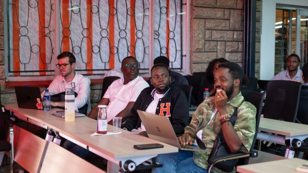 Magothe Innocent at a table with founders at Hackhouse Africa